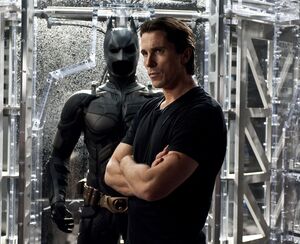 Christian Bale as Bruce Wayne in front of Batsuit